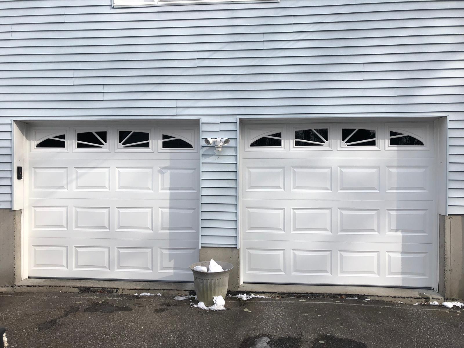 Professional residential garage door installation by SLK Services showing two white sectional garage doors with decorative windows